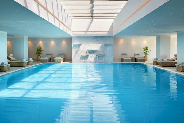 Innenpool des Ikos Aria Hotels mit Loungebereichen und Wasserbrunnen.