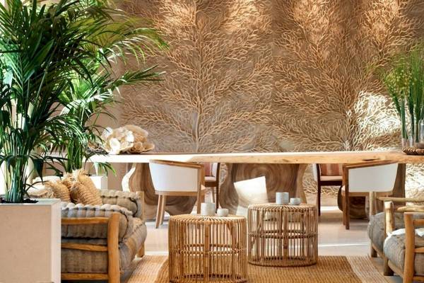 Ein Hotel-Loungebereich mit einem langen Holztisch, umgeben von Stühlen und Pflanzen.