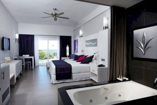 Innenansicht einer Suite im Riu Palace Costa Rica mit großem Bett, Badewanne und Meerblick.