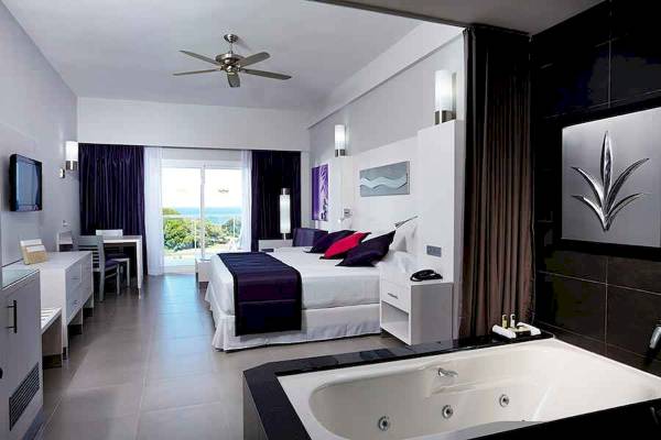 Suite im Riu Palace Costa Rica mit Jacuzzi, Bett, Fernseher und Ausblick.