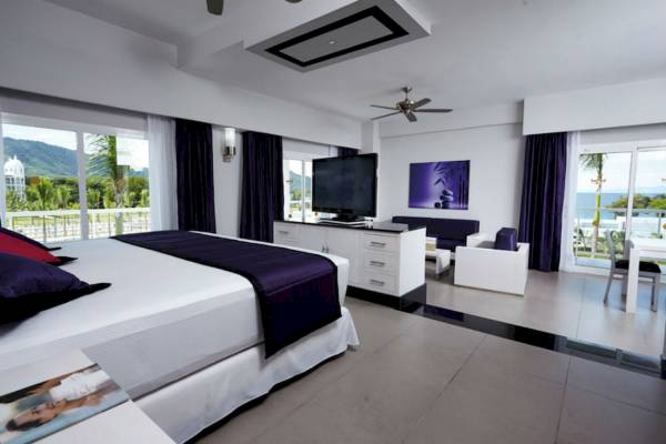 Schlafzimmer im Riu Palace Costa Rica mit Meerblick, modernem Design und großen Fenstern.