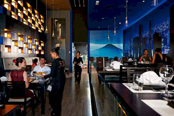 Restaurantszene im Riu Palace Costa Rica mit Gästen, Kellnerin und Einrichtung.