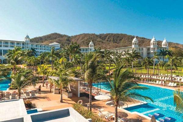 Außenbereich des Riu Palace Costa Rica Hotels mit Swimmingpool und Liegestühlen.