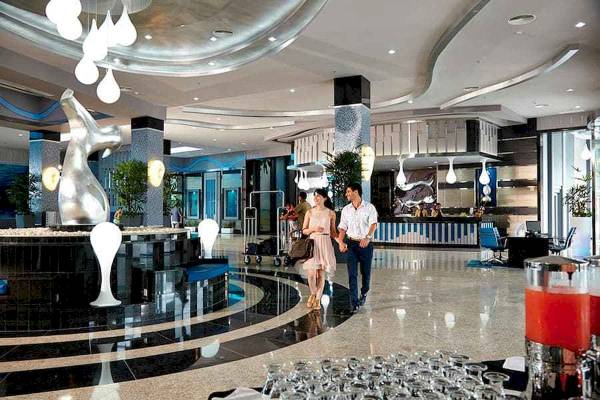 Lobby des Riu Palace Costa Rica Hotels mit silberner Skulptur und zwei Gästen