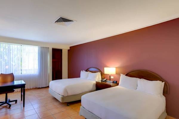 Doppelzimmer im DoubleTree by Hilton Hotel Cariari San Jose mit zwei Betten, Schreibtisch und Fenstern.