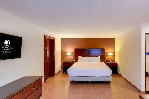 Doppelzimmer im DoubleTree by Hilton Hotel Cariari San Jose mit Bett, Lampen und Fernseher.