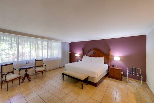 Doppelzimmer im DoubleTree by Hilton Hotel Cariari San Jose mit Bett, Tisch, Stühlen und Nachttischen.
