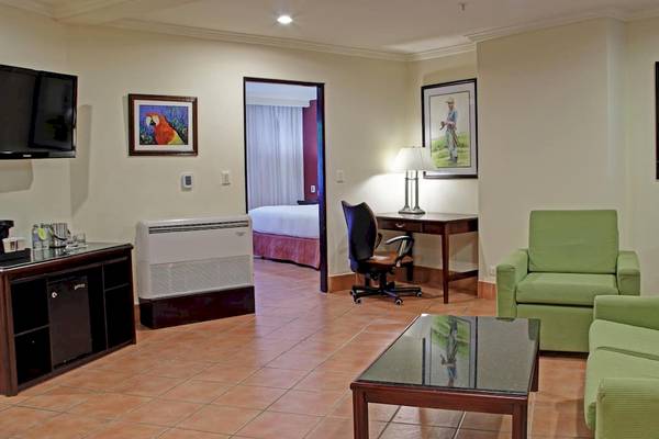 Doppelzimmer im DoubleTree by Hilton Hotel Cariari San Jose mit Wohnzimmer, Schlafzimmer, Schreibtisch und Möbeln.