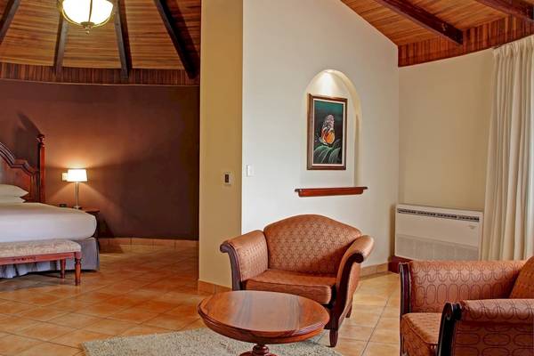 Doppelzimmer im DoubleTree by Hilton Hotel Cariari San Jose mit Bett, Nachttisch, Lampe, Teppich und zwei Sesseln.