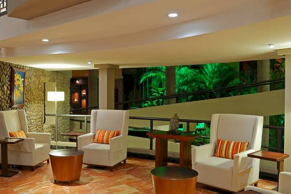 Lobby des DoubleTree by Hilton Hotel Cariari San Jose mit weißen Sesseln, Tischen und einer Steinwand.
