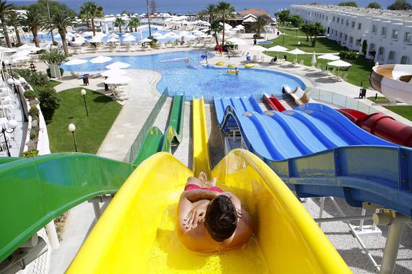 Ein Mann rutscht auf einer gelben Wasserrutsche im Creta Princess Aquapark.