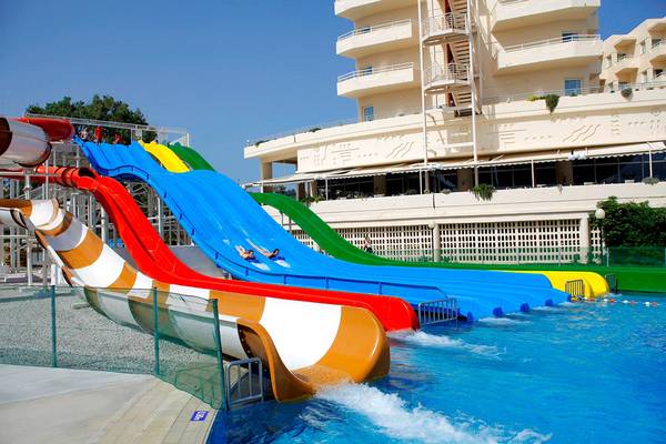 Mehrfarbige Wasserrutschen im Creta Princess Aquapark vor einem großen Hotelgebäude