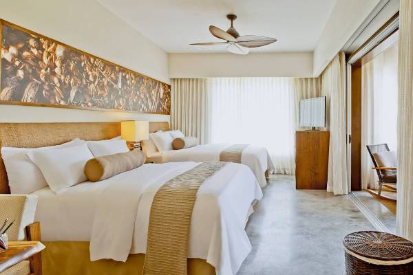 Zwei Betten in einem eleganten Hotelzimmer des El Mangroove, Autograph Collection, mit einem großen Wandbild und modernen Möbeln.
