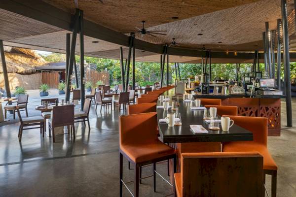Innenbereich des El Mangroove, Autograph Collection Hotels mit Tisch, Stühlen und Bar.