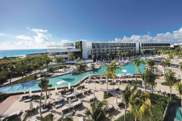 Außenansicht des TRS Coral Hotel mit Swimmingpool, Palmen und Sonnenliegen.