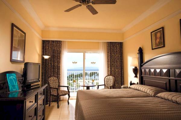 Hotelzimmer im Riu Guanacaste mit Meerblick, Doppelbett, Fernseher, Nachttisch und Balkon.