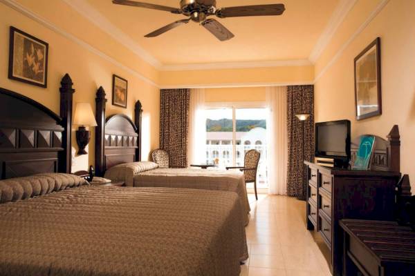 Doppelzimmer im Riu Guanacaste Hotel mit zwei Betten, Fernseher und Balkon.