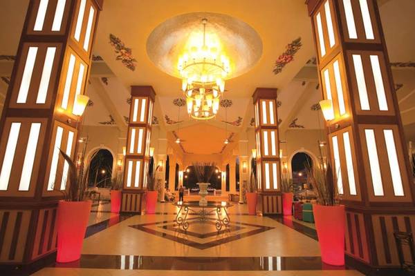 Empfangsbereich des Riu Guanacaste Hotels mit einer großen Kronleuchter und roten Pflanzkübeln