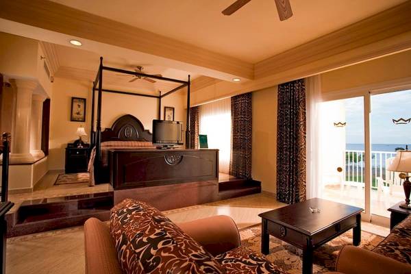 Innenansicht einer Suite im Riu Guanacaste Hotel mit Bett, Wohnzimmer und Meerblick.