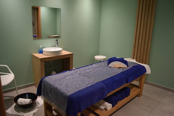 Spa-Behandlungsraum im Creta Princess Aquapark & Spa mit grünen Wänden, einem Tisch, einer Schale und Handtüchern.