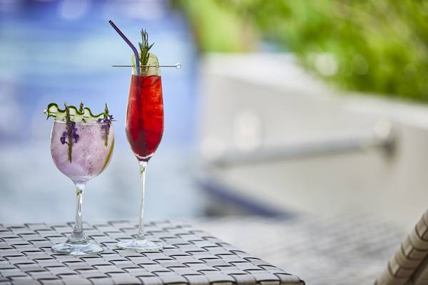 Zwei Cocktails mit lavendelfarbenem Getränk und grünen Dekorationen auf einem Tisch am Pool.