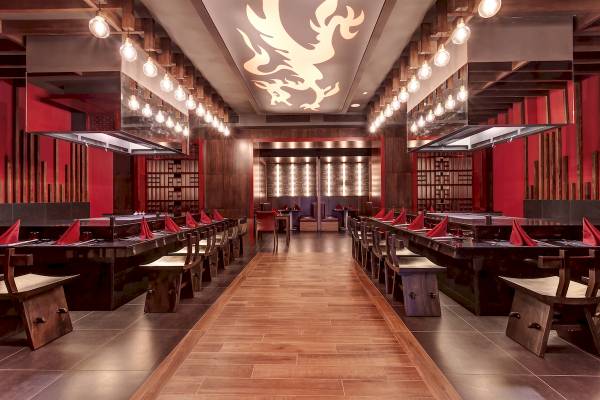 Innenansicht des Restaurants im Planet Hollywood Beach Resort mit roten Wänden, hölzernem Boden und langen Tischen.