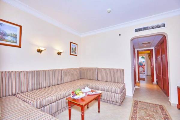 Wohnzimmer einer Hotelsuite mit einem L-förmigen Sofa, einem Tisch und Früchten darauf.