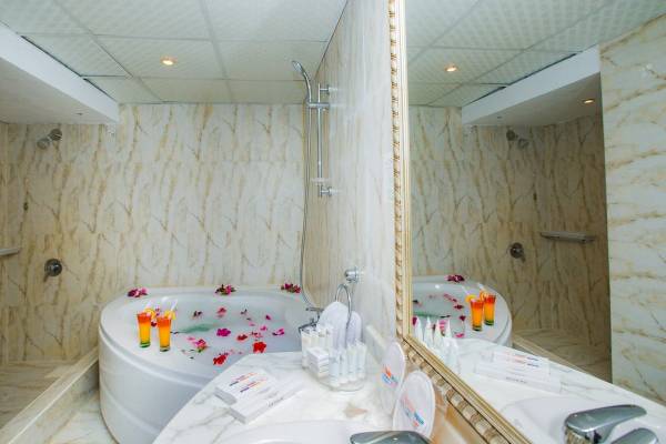 Badezimmer des Titanic Beach Spa & Aqua Park Hotels mit Badewanne, Dusche und Rosenblättern
