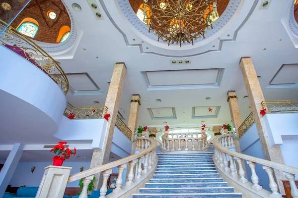 Innenansicht des Hotel-Empfangsbereichs mit Treppe und Kronleuchter