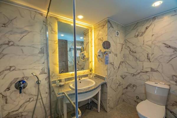 Badezimmer im Titanic Resort & Aqua Park mit Marmorfliesen, Dusche, Spiegel und Toilette.