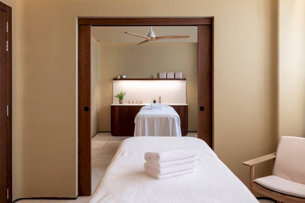 Massageraum im Zel Mallorca Hotel mit weißen Handtüchern und einem Stuhl.