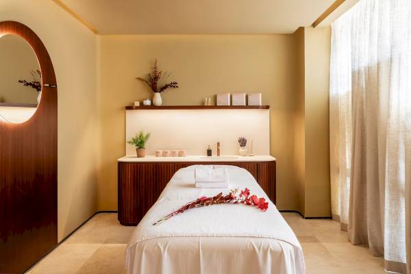 Spa-Behandlungsraum im Zel Mallorca mit Tisch, Liege, Deko und Pflanzen.