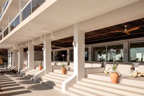 Lounge-Bereich des Zel Mallorca Hotels mit weißen Möbeln, Pflanzen und Sonnenschirmen.