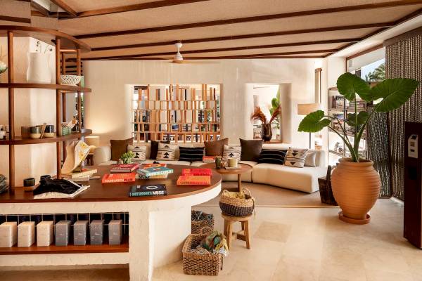 Innenbereich des Zel Mallorca Hotels mit Wohnzimmermöbeln, Büchern, Pflanzen und Dekor.