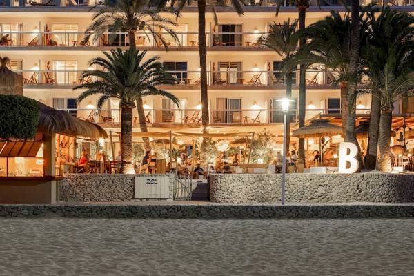 Außenansicht des Zel Mallorca Hotels am Strand mit Beleuchtung und Gästen.
