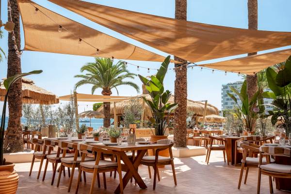 Sitzplätze im Freien im Zel Mallorca Hotel Restaurant mit Blick auf das Meer und Palmen.