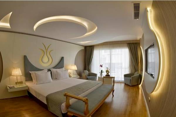 Schlafzimmer im Arden City Hotel mit Doppelbett, Sesseln und dekorativen Wandleuchten