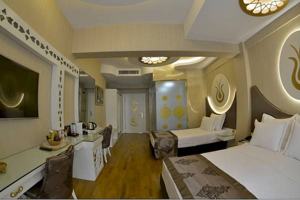 Innenansicht eines Zimmers im Arden City Hotel mit zwei Betten, Schreibtisch und Fernseher.