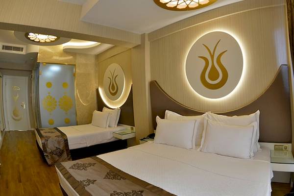 Hotelzimmer im Arden City mit zwei Betten, weißen Kissen und dekorativen Wandlampen.