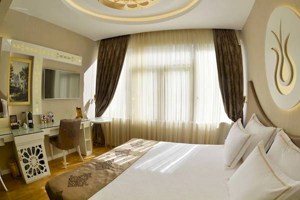Hotelzimmer im Arden City mit großem Bett, weißem Bettzeug, Schreibtisch und Fernseher.