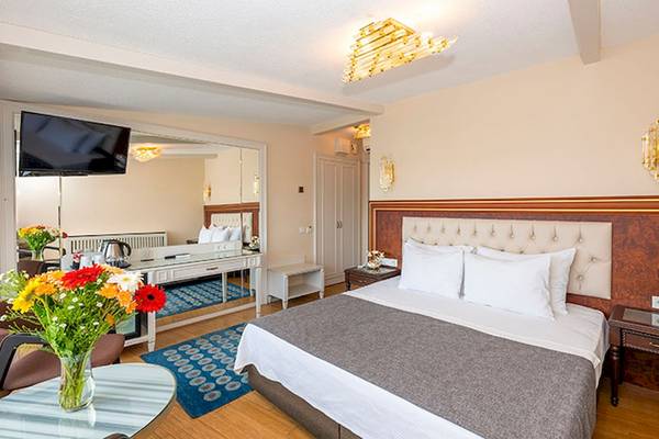 Hotelzimmer im Arden City Hotel mit Doppelbett, Fernseher und Blumenvase.