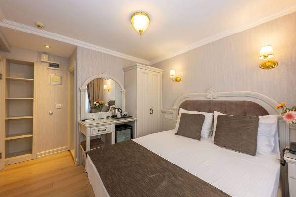 Innenansicht eines Hotelzimmers im Arden City Hotel mit Bett, Tisch und Spiegel.