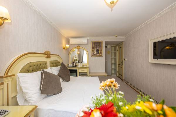 Schlafzimmer im Arden City Hotel mit Bett, Blumen, Spiegel und Klimaanlage.