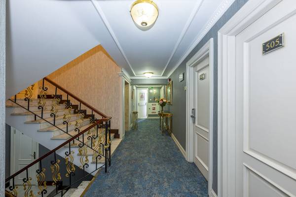 Korridor im Arden City Hotel mit Treppen, blauem Teppich und Zimmertür mit Nummer 505.