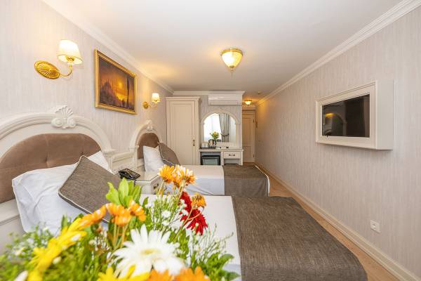 Doppelzimmer im Arden City Hotel mit zwei Betten, Blumen, und einem Fernseher an der Wand.