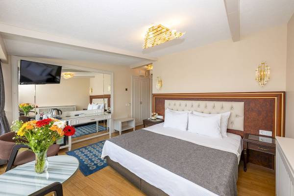 Schlafzimmer im Arden City Hotel mit Doppelbett, Fernseher und Blumenvase auf dem Tisch.