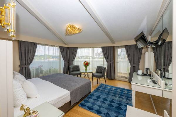 Schlafzimmer im Arden City Hotel mit Bett, Stühlen, Tisch und Fenstern mit Blick auf die Stadt