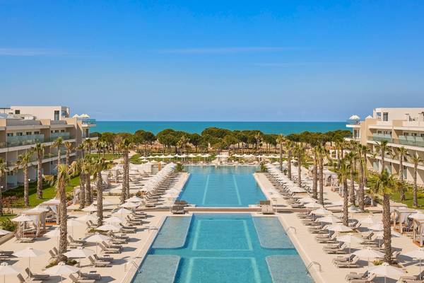 Außenansicht des Melia Durres Albania Resorts mit Swimmingpool und Sonnenliegen.