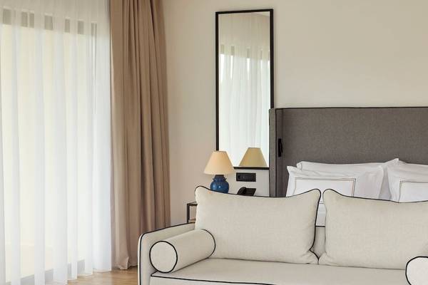Schlafzimmer des Melia Durres Albania Hotels mit Doppelbett, Kissen, Nachttischen und Lampen.
