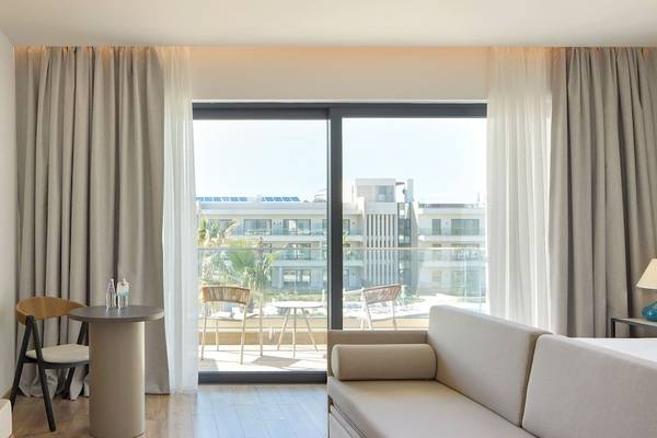 Ein modernes Hotelzimmer im Melia Durres Albania mit Blick auf ein Gebäude und einen Garten.